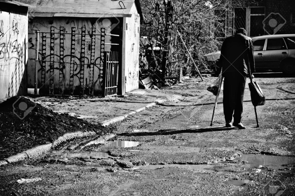 9489303 A Sick Poor Man With Crutches Walking Down The Street Rear View Black And White